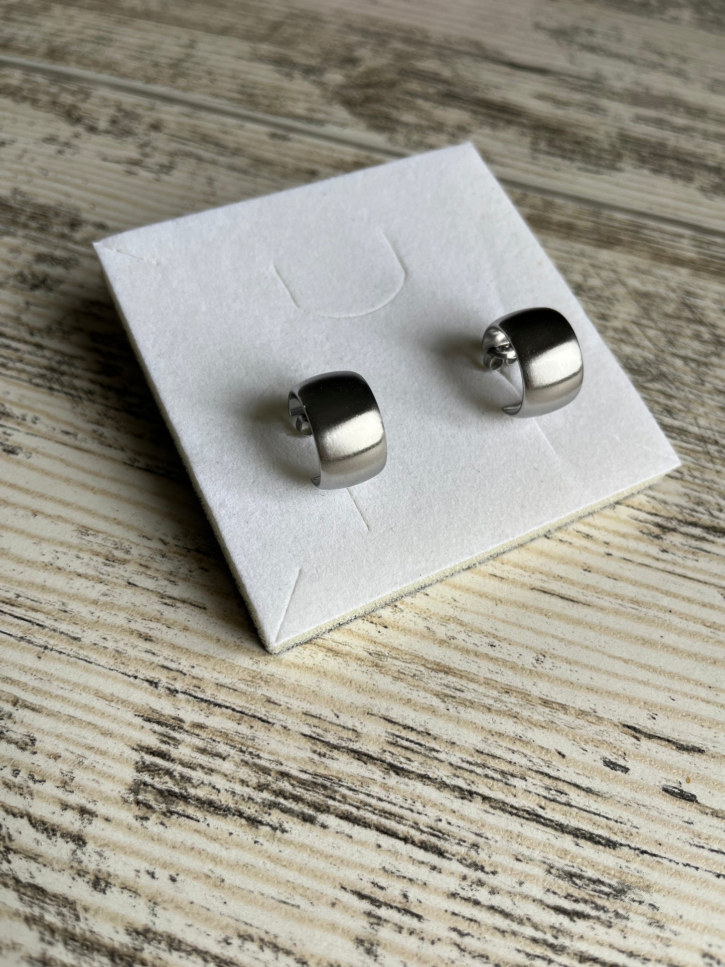 Boucles d'oreilles type créoles en acier inoxydable composées d'un anneau large et plat avec un effet brossé.