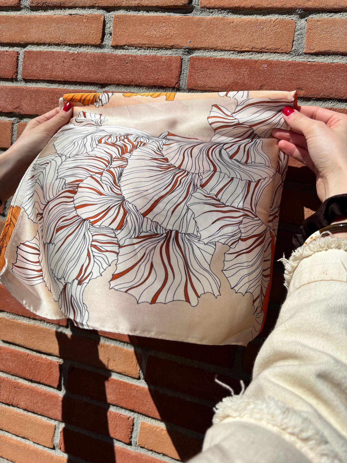 Accessoire mode incontournable : foulard en soie aux motifs floraux orange et blanc, pour une allure féminine et pleine de charme.