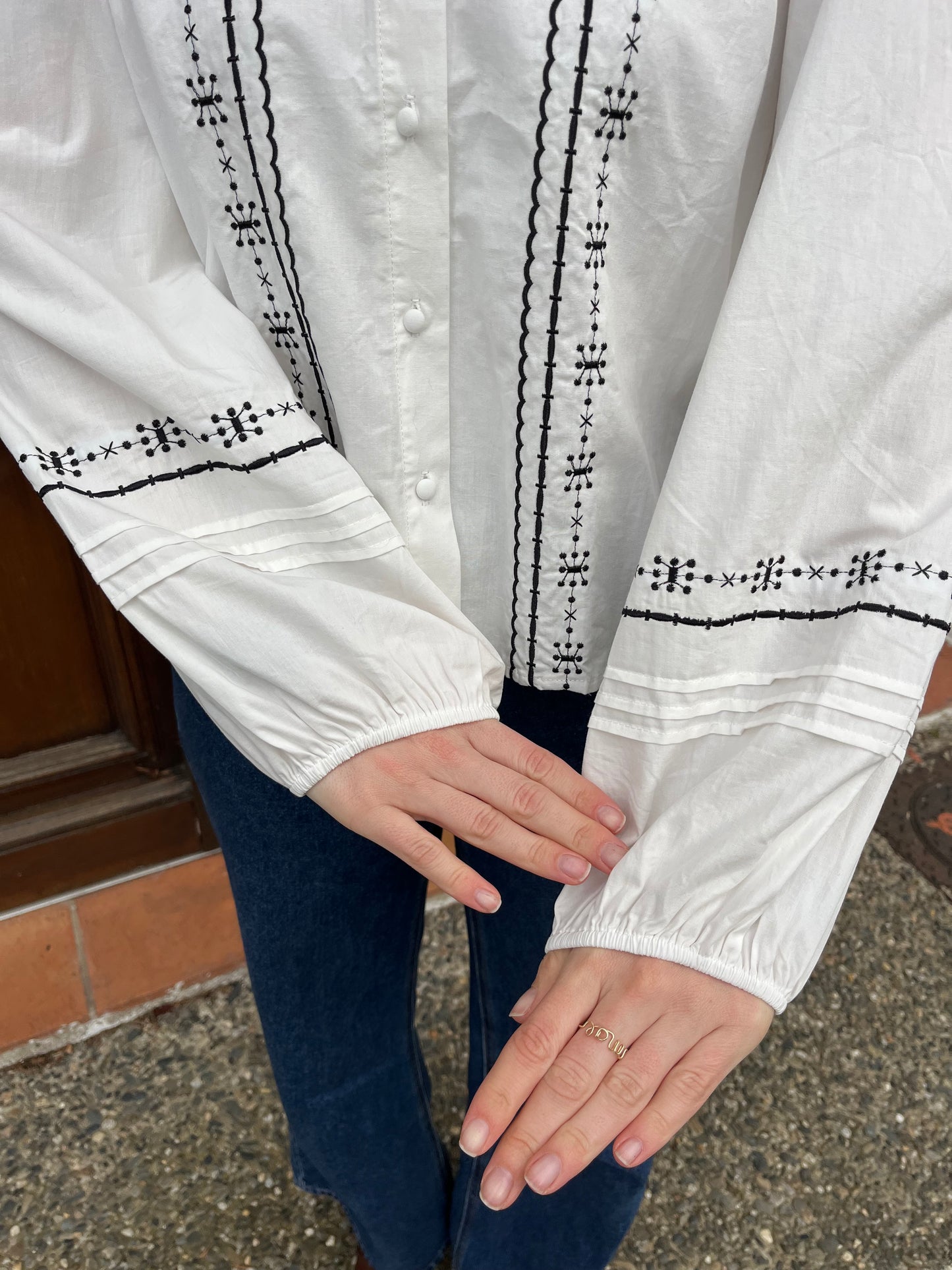 Blouse en coton de couleur blanche avec broderie noire sur la blouse et bouton sur le devant taille cintrée prendre sa taille habituelle