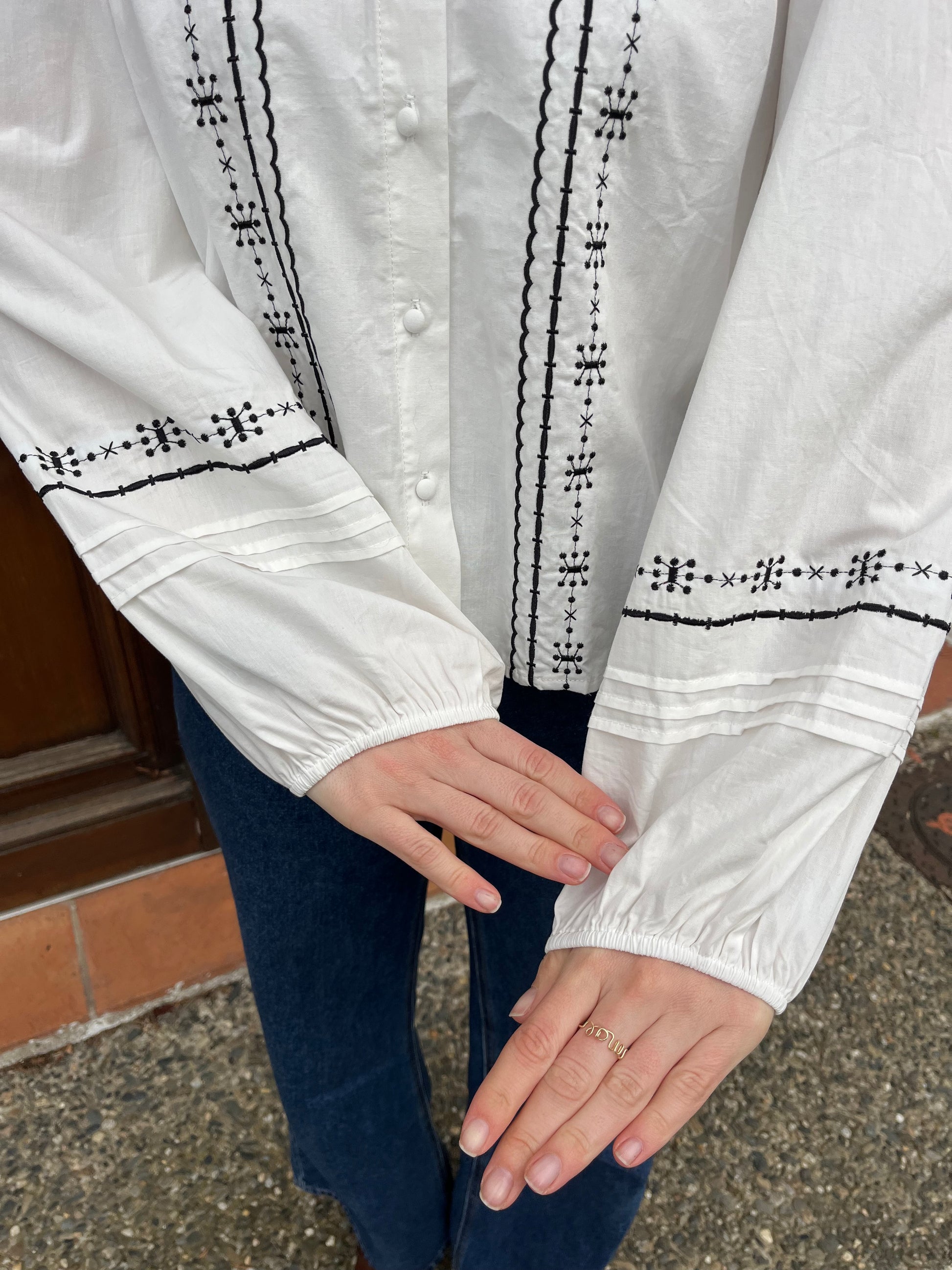 Blouse en coton de couleur blanche avec broderie noire sur la blouse et bouton sur le devant taille cintrée prendre sa taille habituelle