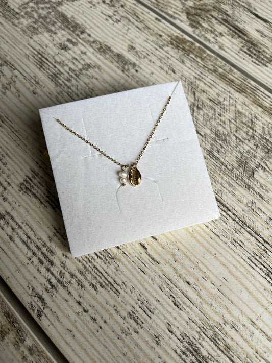 Collier sur chaîne en acier inoxydable composé d'un petit pendentif cauri et de 2 petites perles d'eau douce.
