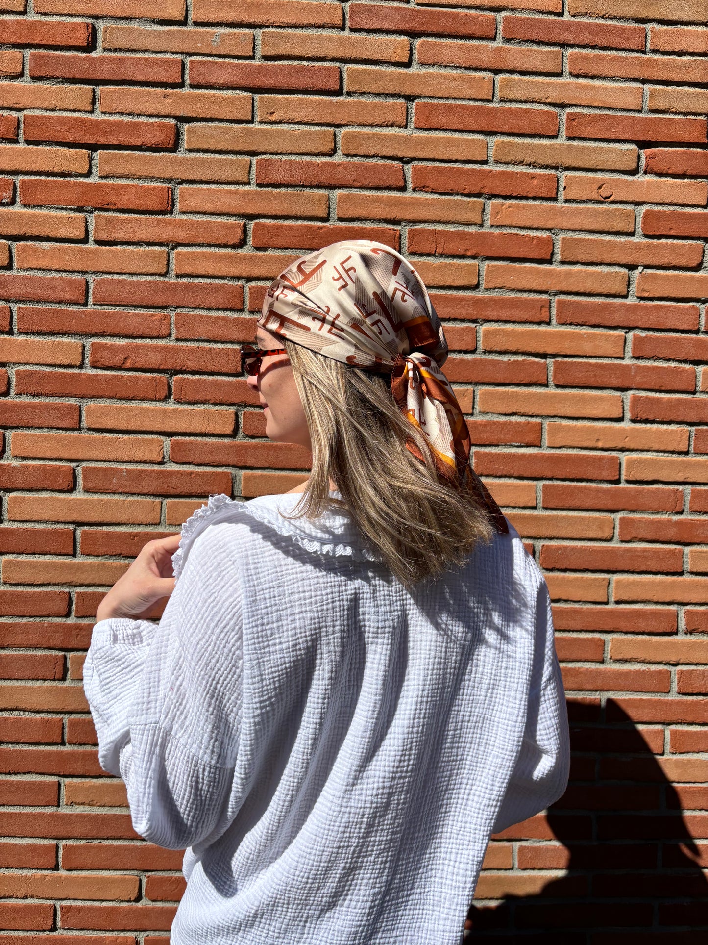 Élégant foulard en soie couleur marron, motifs délicats, accessoire tendance et sophistiqué pour femme.