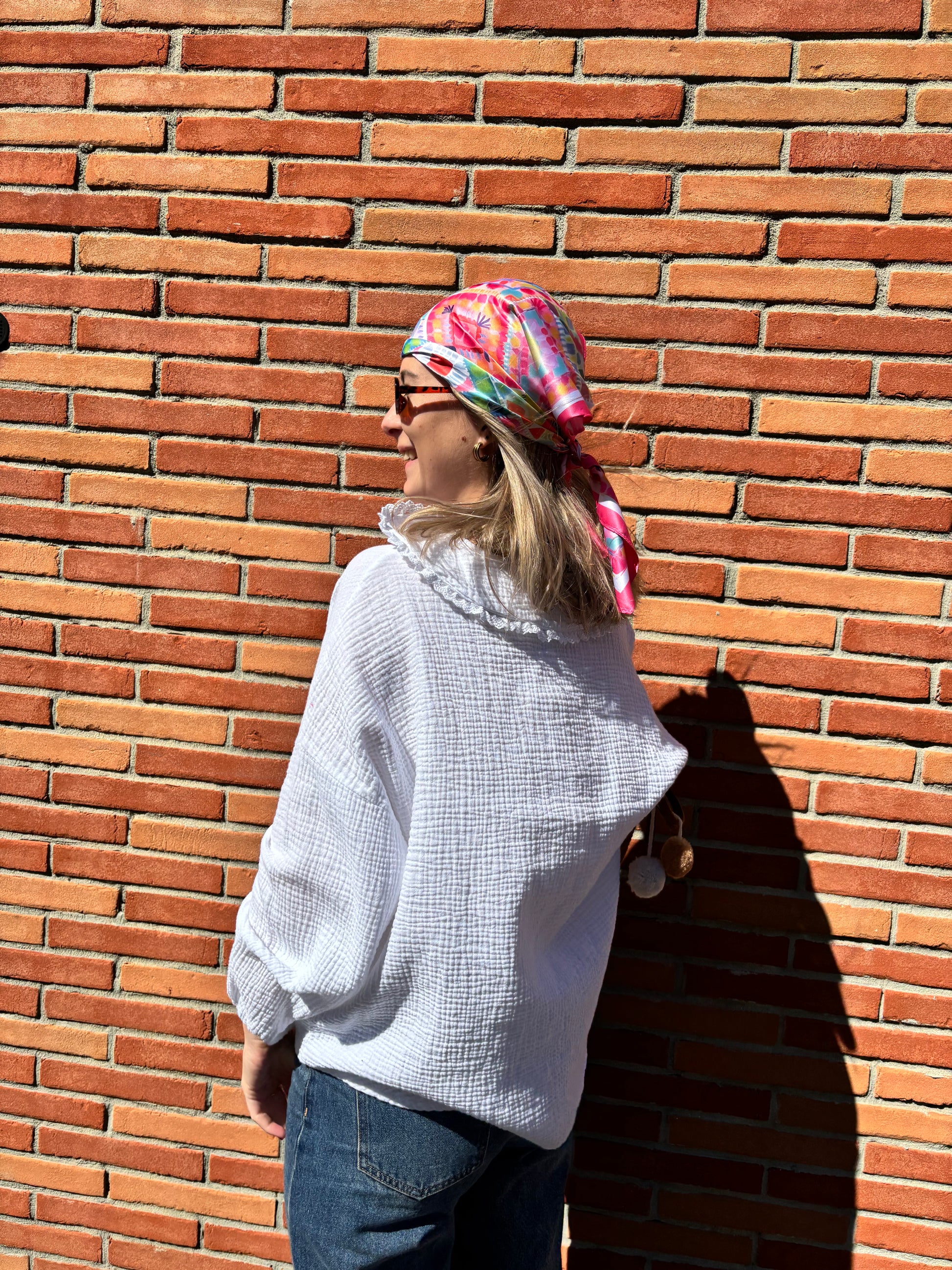 Détail d’un foulard rose à motifs géométriques, texture douce et finition soignée, accessoire de mode tendance
