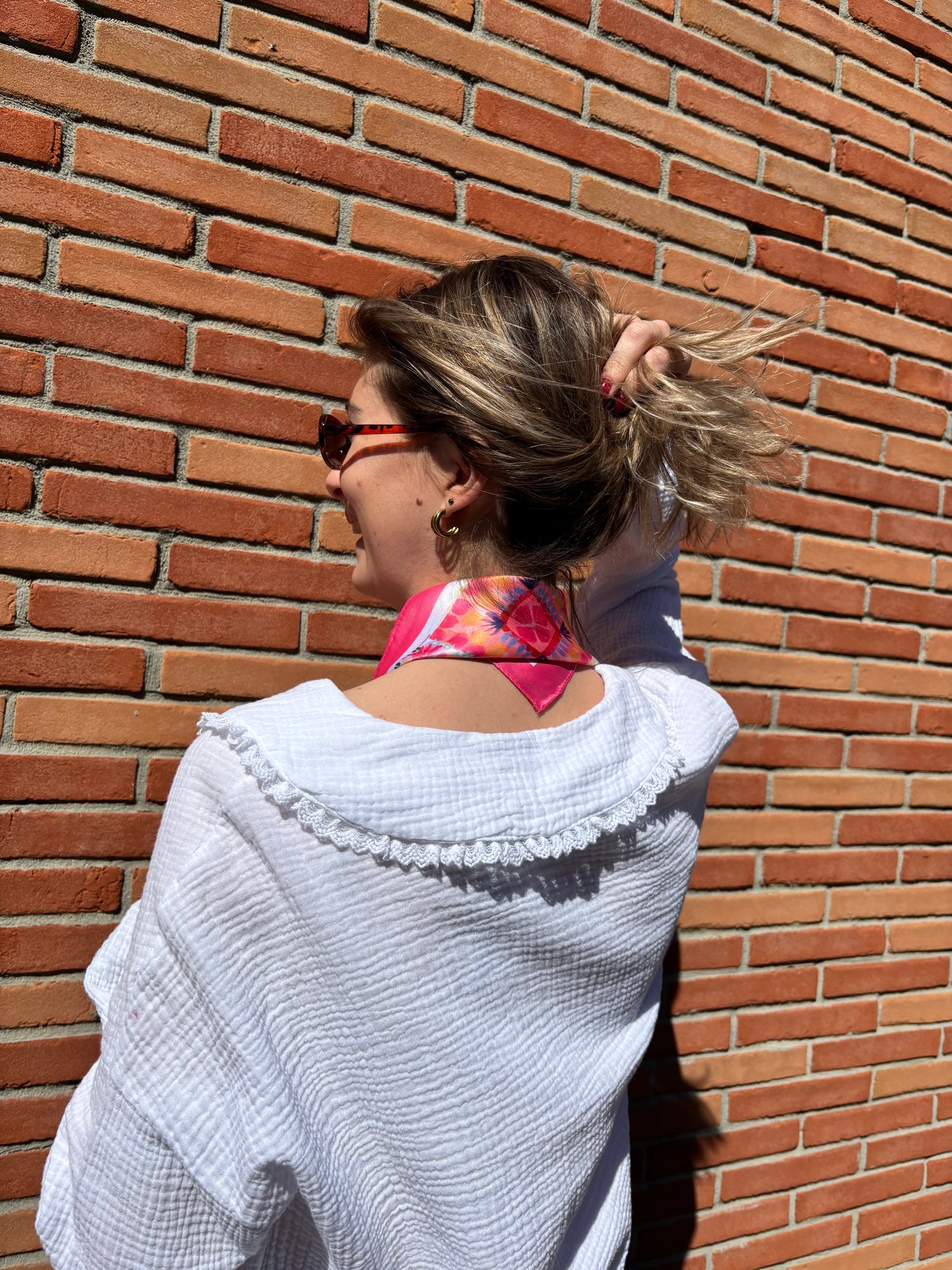 Femme portant un foulard rose à motifs géométriques, style chic et féminin, parfait pour compléter une tenue élégante