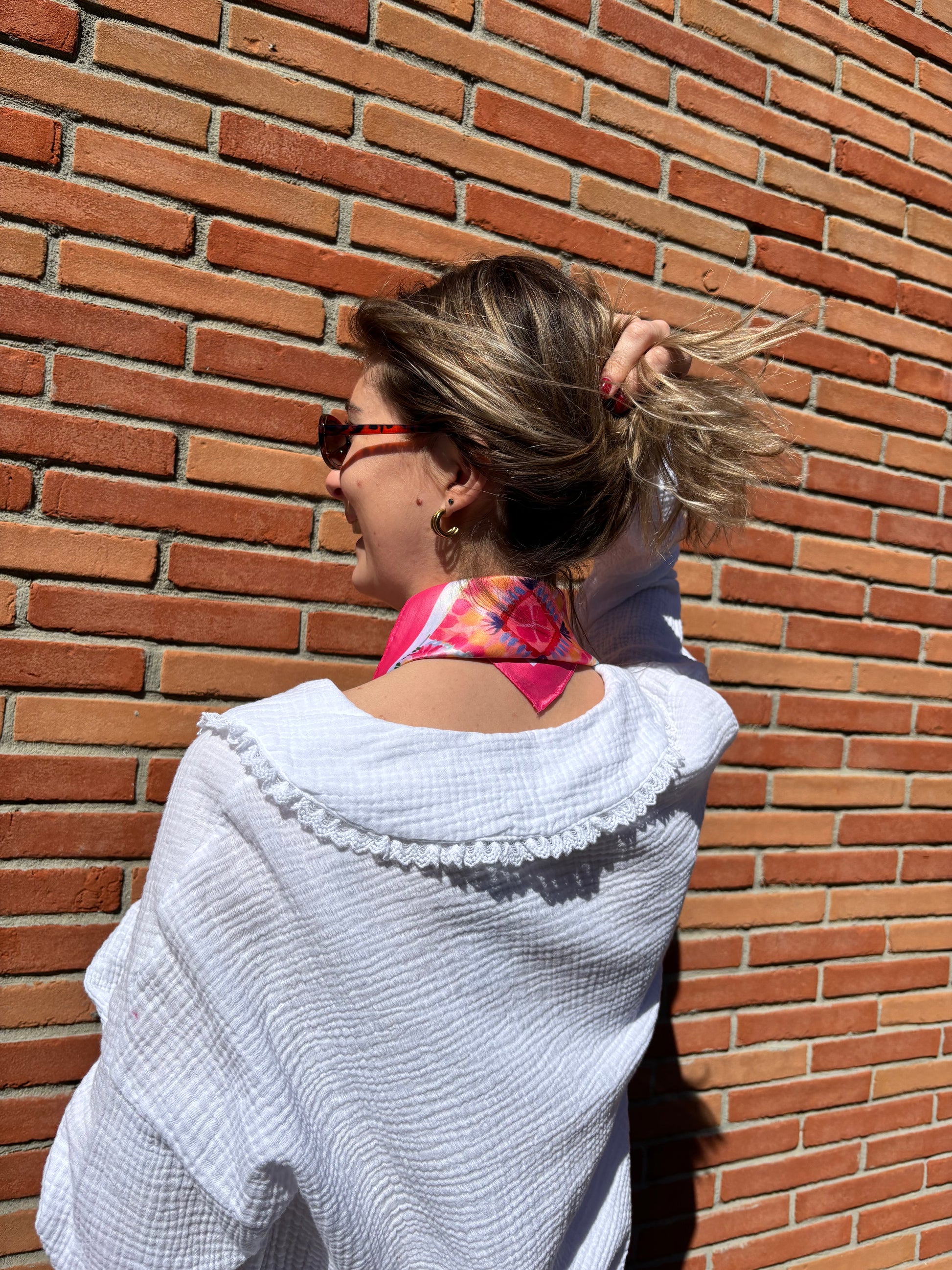 Femme portant un foulard rose à motifs géométriques, style chic et féminin, parfait pour compléter une tenue élégante
