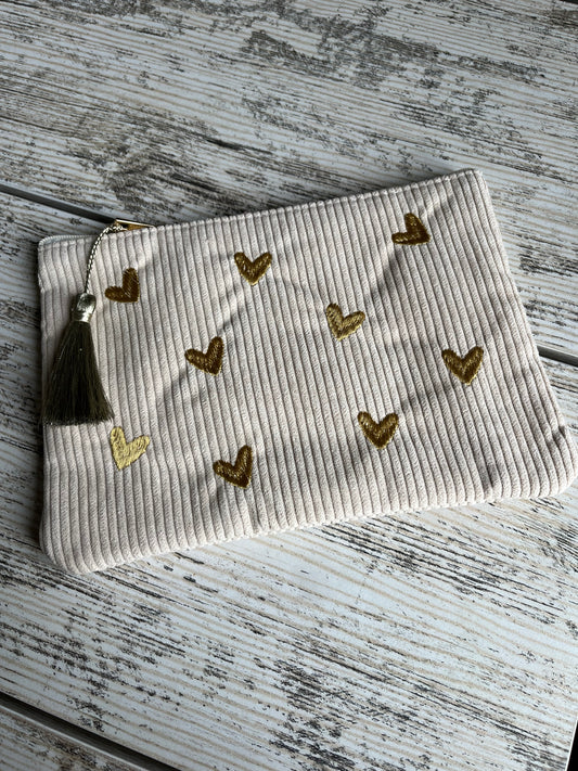 Pochette multi-usages, pratique pour y ranger tout type d'affaires (toilettes, maquillage etc.) avec son pompon décoratif. Des coeurs sont brodés sur le dessus de la trousse en velours côtelé et de jolis motifs floraux sont imprimés à l'intérieur de la pochette.